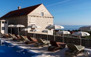 a row of chairs and umbrellas next to a swimming pool at Palace Natali in Dubrovnik