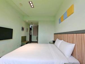 a bedroom with a large white bed and a flat screen tv at 好室行旅House inn 金門大學旁 近市區 in Jinning