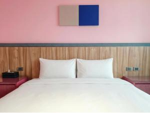 a bedroom with a large white bed and a pink wall at 好室行旅House inn 金門大學旁 近市區 in Jinning