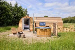 a small wooden cabin with a hot tub in a field at Waters Edge Cabin in Helmsley