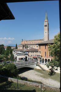 a bridge over a river with a building with a clock tower at LEON D'ORO - Art Hotel in Pieve di Soligo