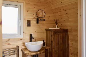 a bathroom with a white bowl sink in a wooden wall at Waters Edge Cabin in Helmsley