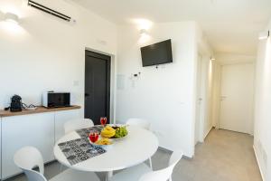 a white dining room with a white table and chairs at GiuMar Apartments Acitrezza in Aci Catena
