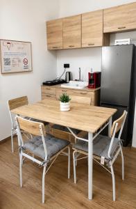 a kitchen with a wooden table with chairs and a refrigerator at LOFT EMILIA - la tappa perfetta tra Bologna e Ravenna - SELF CHECK-IN in Castel Bolognese +3 photos
