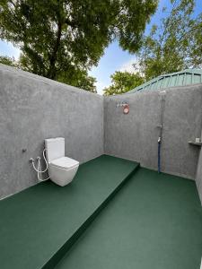 a bathroom with a toilet in a concrete wall at Green Techno Villa in Kitulkote
