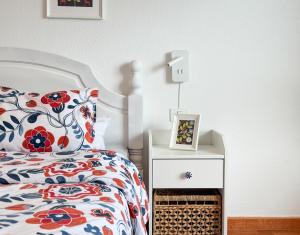 a bedroom with a bed with a floral bedspread and a night stand at Apartamento Maye in Bajamar