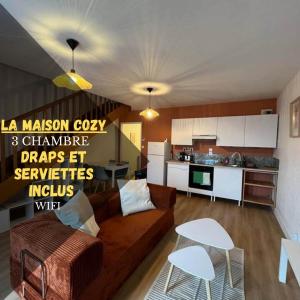 a living room with a brown couch and a kitchen at Maison cozy in Saint-Brieuc