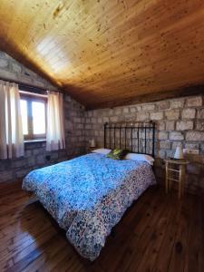 a bedroom with a bed and a stone wall at Hotel Rural del Médico in Regumiel de la Sierra