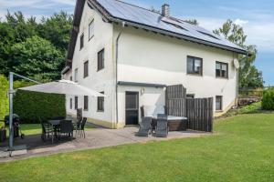 a white house with a table and chairs and an umbrella at Eifel Dream Zingsheld in Fleringen