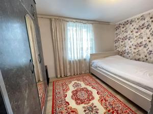 a small bedroom with a bed and a rug at Sun Garden Guest House in Ak-Say