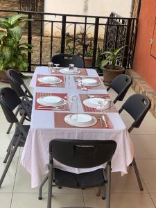 a long table with chairs and plates on a balcony at Auberge mfuma in Kisantu
