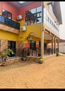 a yellow building with a balcony on the side of it at Auberge mfuma in Kisantu