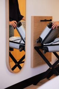 a woman is looking at her reflection in a mirror at B&B HOTEL Bastia in Bastia