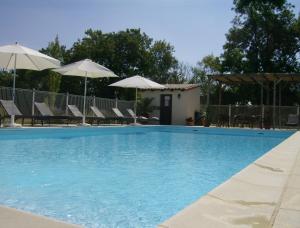 a swimming pool with chairs and umbrellas at Gites de Cognac in Bréville