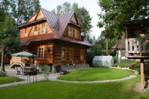 una cabaña de madera con un patio de césped delante de ella en Dom Tomusik, en Zakopane
