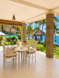 a patio with a table and chairs and the ocean at Relax Bali Resort, Diving & SPA, ocean front in Tulamben