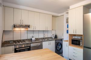 a kitchen with white cabinets and a wooden table at Majordoms Ponent in Banyoles