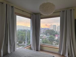 a bedroom with a large window with a view of a city at Altura House in Almaty