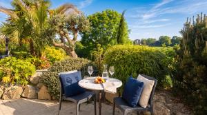 a table and two chairs with wine glasses on a patio at Les sapins verts - vue haras in Saint Lo