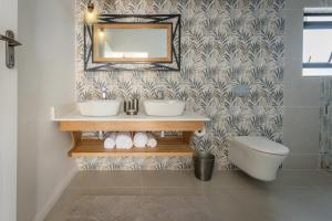 a bathroom with a sink and a mirror and a toilet at Waterfalls Lodge in Victoria Falls +15 photos