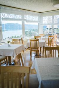 a dining room with tables and chairs and windows at Hotel Ossiacher See in Stiegl