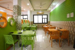a restaurant with green walls and tables and chairs at Hotel highway inn in Gandhidham