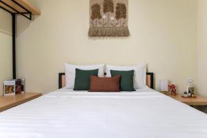a bedroom with a white bed with green and white pillows at Rooms at Calma Villa Panorama, Batu Malang in Batu +10 photos