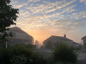 a misty sunrise in a small village with buildings at La Maison des Sources in Édon +5 photos