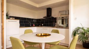 a kitchen with a white table and green chairs at Les sapins verts - vue haras in Saint Lo
