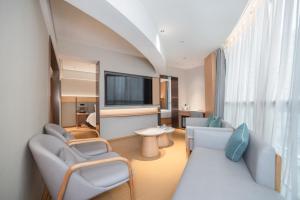 a living room with two chairs and a tv at JI Hotel Beijing Panjiayuan in Beijing