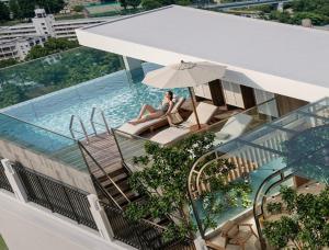a woman sitting on a balcony next to a swimming pool at La Passion Elegance Hotel & Spa in Hanoi