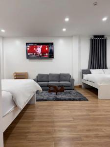 a bedroom with a couch and a tv on the wall at AOC HOTEL in Cao Lãnh