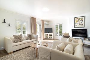 a living room with white furniture and a tv at Winelands Golf Lodges 28 in Stellenbosch +39 photos