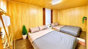 two beds in a room with wooden walls at LaLa Hill in Ấp Kim Thạch