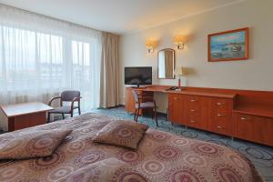 a hotel room with a bed and a desk and a television at Hotel Lidia - część Economy in Darłowo