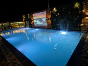 a large blue swimming pool at night with a large screen at Red Fox by Lemon Tree Hotels, Alwar in Alwar
