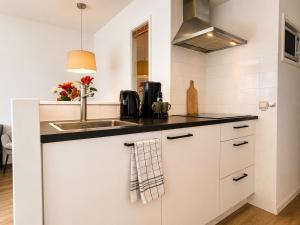 a kitchen with white cabinets and a sink at Prins Prachtig Amelander Kaap 97 in Hollum