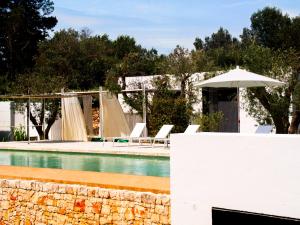 a swimming pool with chairs and an umbrella at Cocotrullo in Ostuni