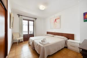 a white bedroom with a bed and a chair at Vives Ref 9002 in Cala Bona