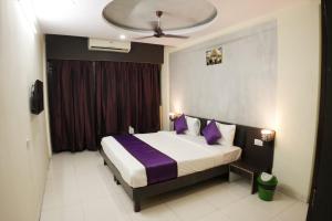 a bedroom with a large bed with purple pillows at Hotel highway inn in Gandhidham