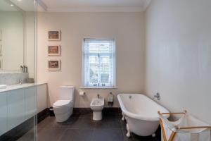 a bathroom with a tub and a toilet and a sink at Purple House Accommodations in Cape Town