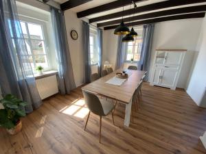 a dining room with a wooden table and some windows at Rheinhessen Auszeit in Wendelsheim