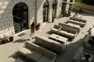 a woman walks past a row of tables and benches at Hotel Štacija in Kaštela