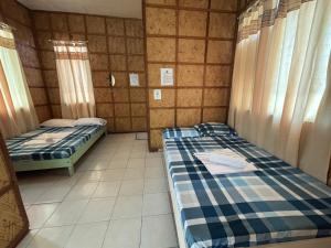 a room with two beds in a room with curtains at Medelaine's Beach Resort in Puerto Galera