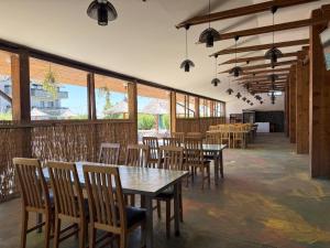 a restaurant with wooden tables and chairs and windows at Greenstone Land - Corbu in Năvodari