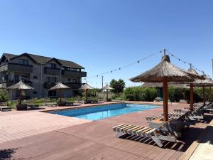 a swimming pool with lounge chairs and an umbrella at Greenstone Land - Corbu in Năvodari