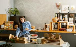 a woman standing in a store with a plate of food at Hotel Štacija in Kaštela
