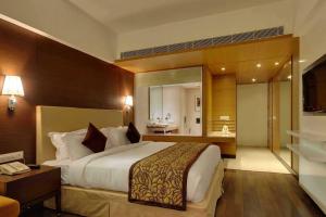 ein Hotelzimmer mit einem großen Bett und einem Badezimmer in der Unterkunft Hotel Platinum in Rajkot + 30 Fotos