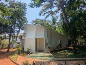 a white house with a tree in front of it at Trisara Boutique Stay in Mysore