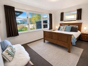 a bedroom with a bed and a large window at Redwoods Retreat Rotorua Private 3BR Home in Rotorua